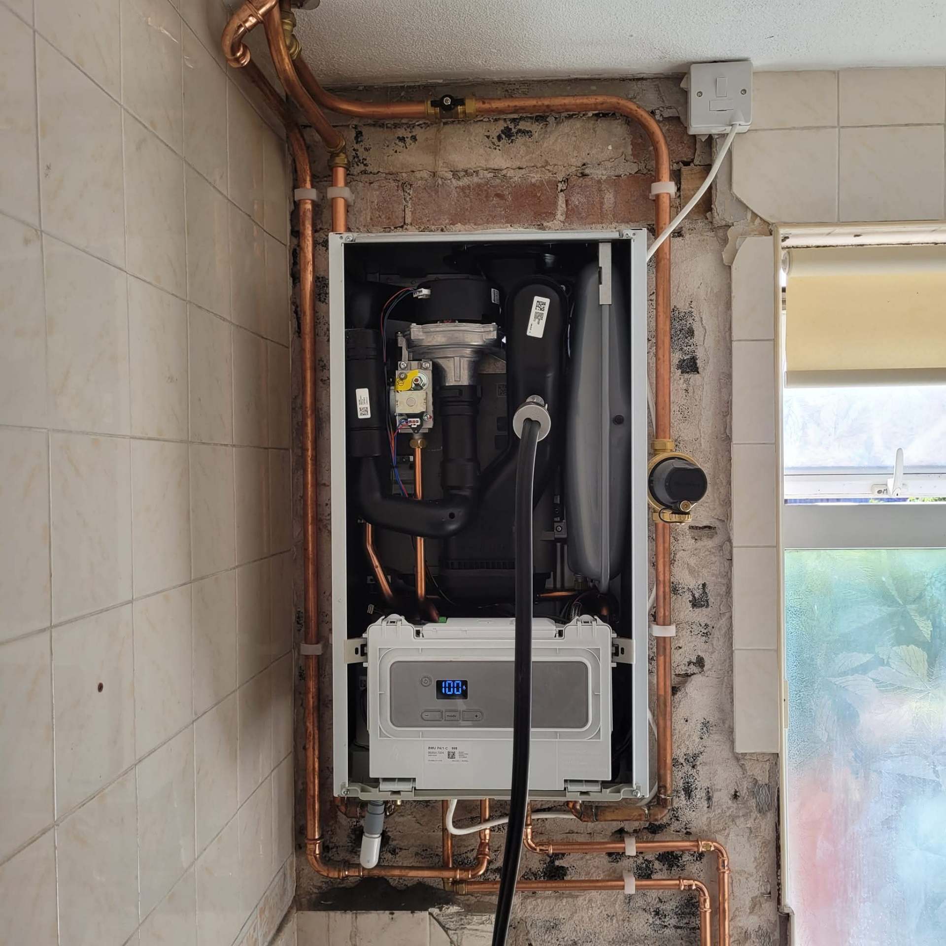 Boiler installation with copper drops and gas tee in a tiled utility room