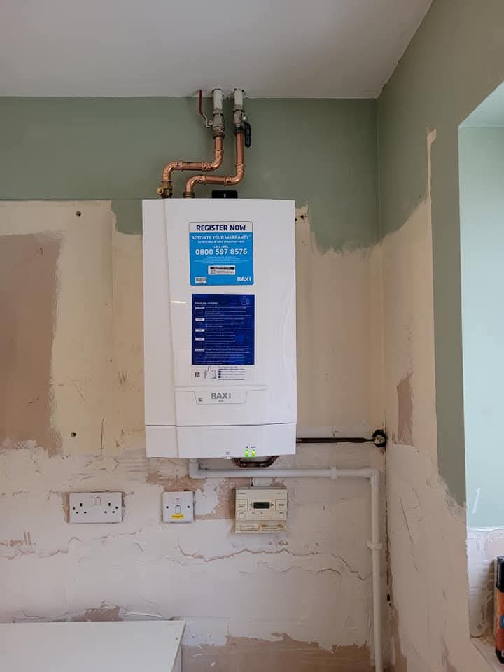 New combi boiler installed on a freshly plastered wall, ready for commissioning