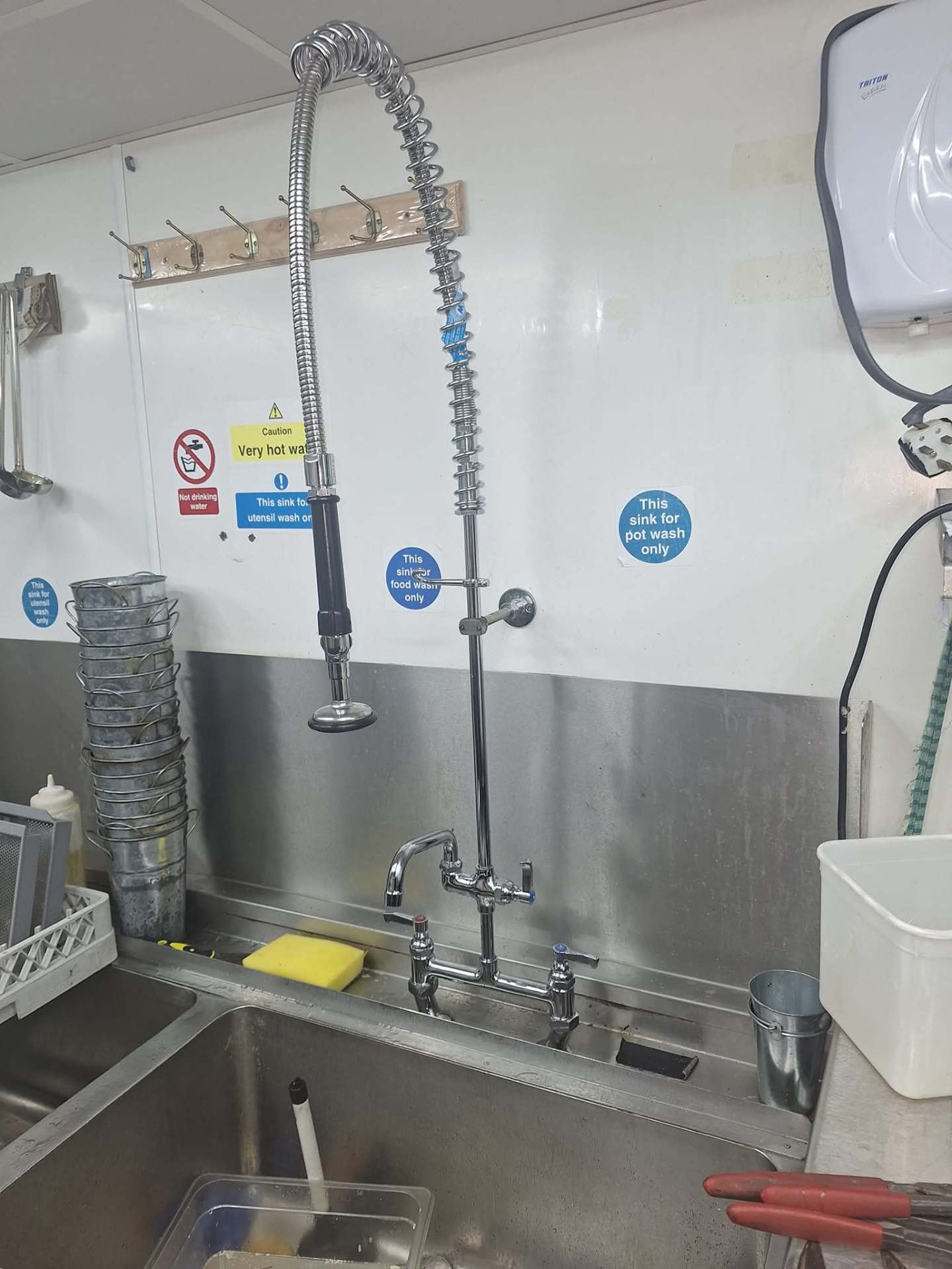 Commercial kitchen pre-rinse spray and stainless steel sink plumbed in